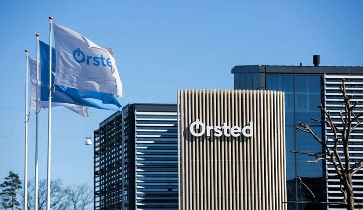 Cartel de Ørsted y dos banderas en el exterior de una de las oficinas de Ørsted en un día soleado.
