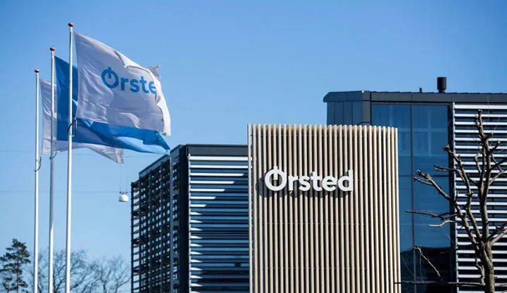 Cartel de Ørsted y dos banderas en el exterior de una de las oficinas de Ørsted en un día soleado.