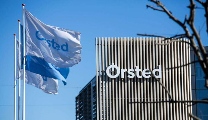 Three Ørsted flags waving outside an Ørsted office on a sunny day.