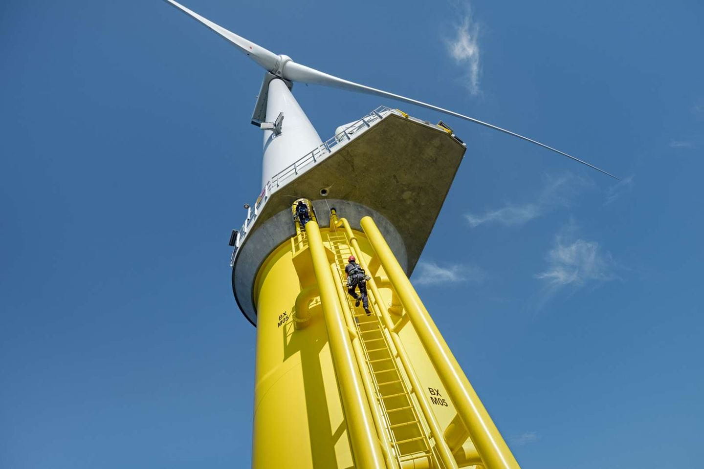 Technician climbing a ladder on an offshore wind turbine