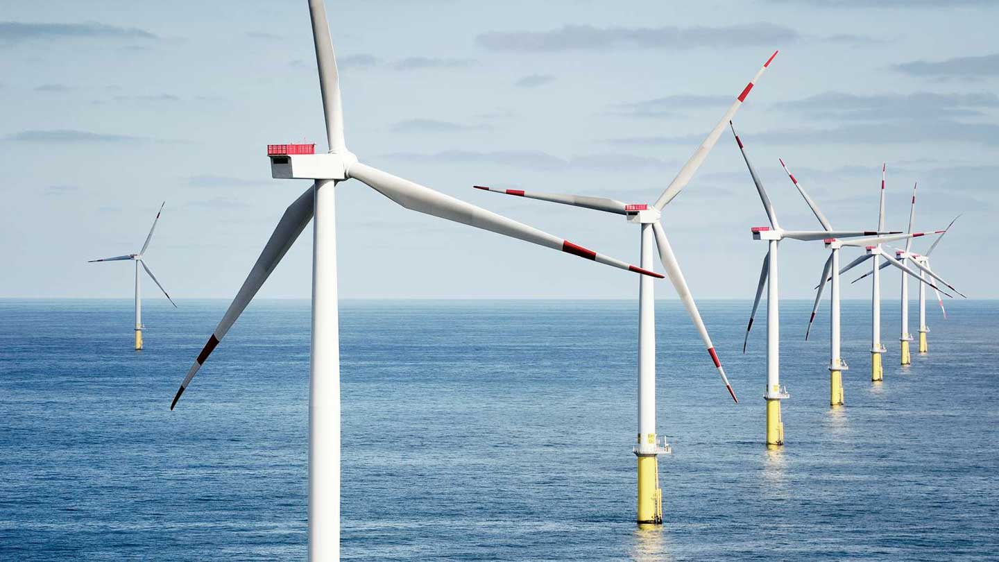 A row of offshore wind turbines at sea.