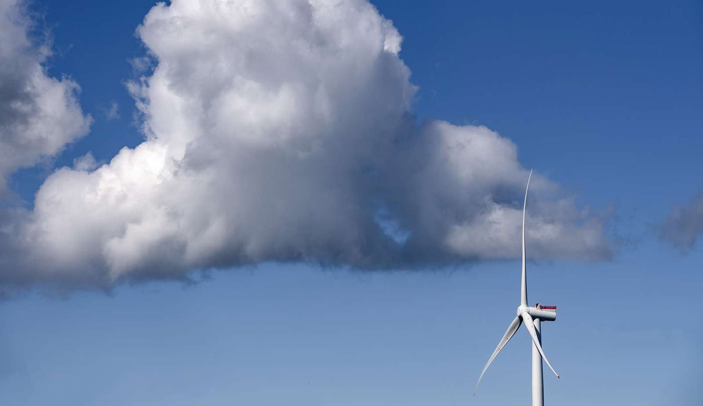 A wind turbine in front of a dark cloud.
