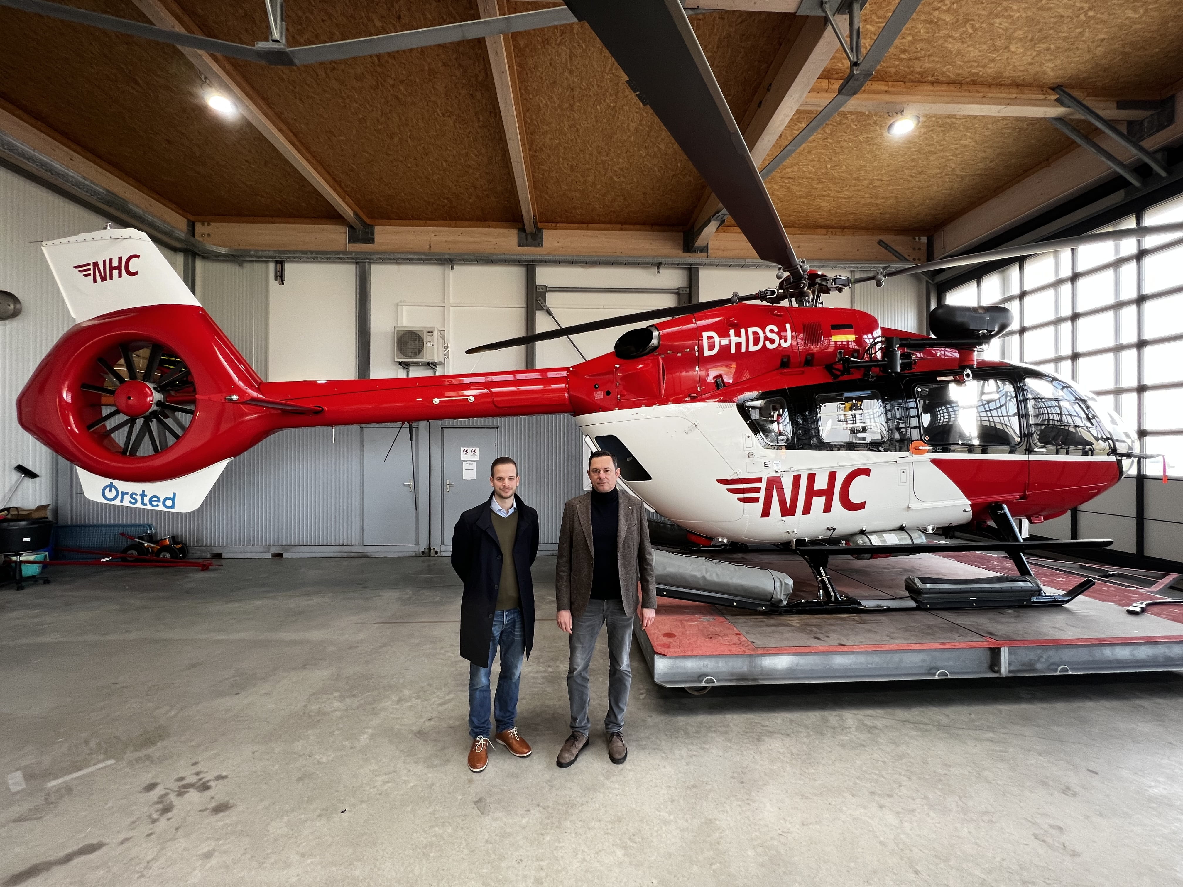 Thijs Schless, Leiter der Betriebsführung von Ørsted am Standort Norddeich, und Armin Ortmann, Geschäftsführer der Northern Helicopter GmbH, vor dem Helikopter 