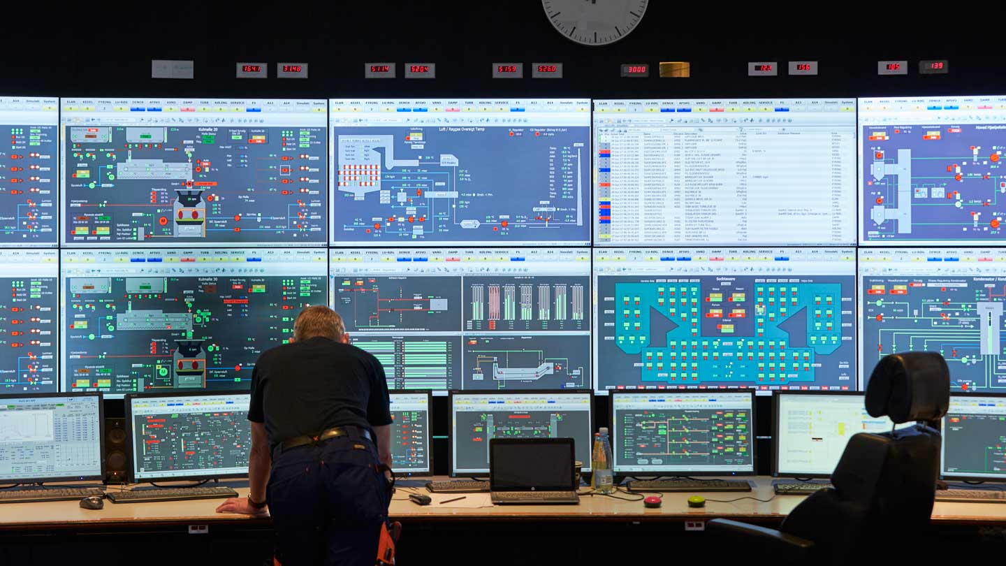 Worker standing in front of a control room monitor at a power plant.