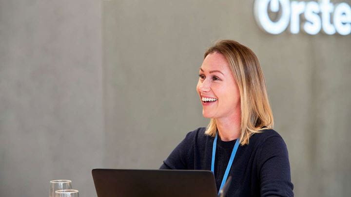 A smiling female Ørsted employee working in an office offers an example of an approved image from our U.S. image library.