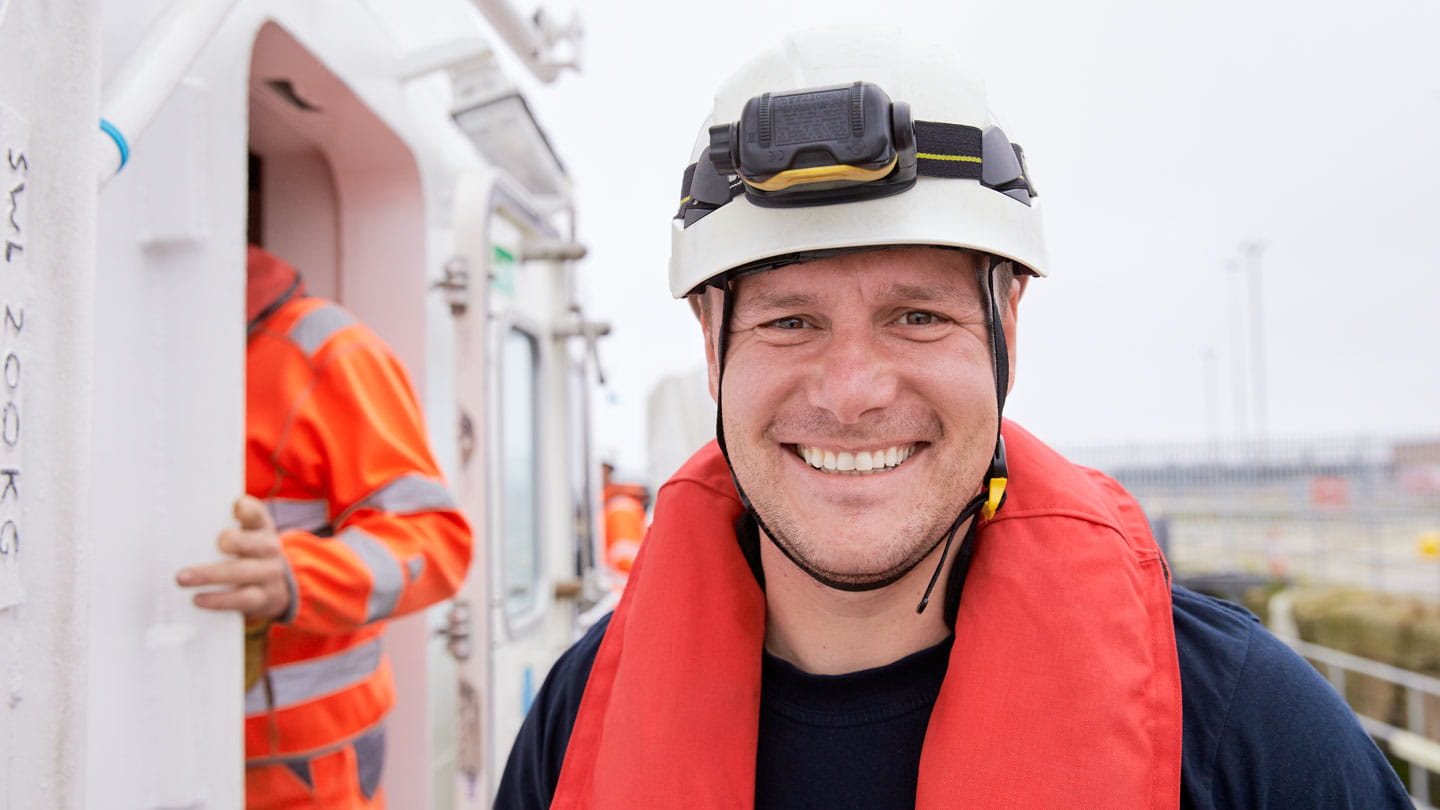 man smiles big while wearing safety gear 
