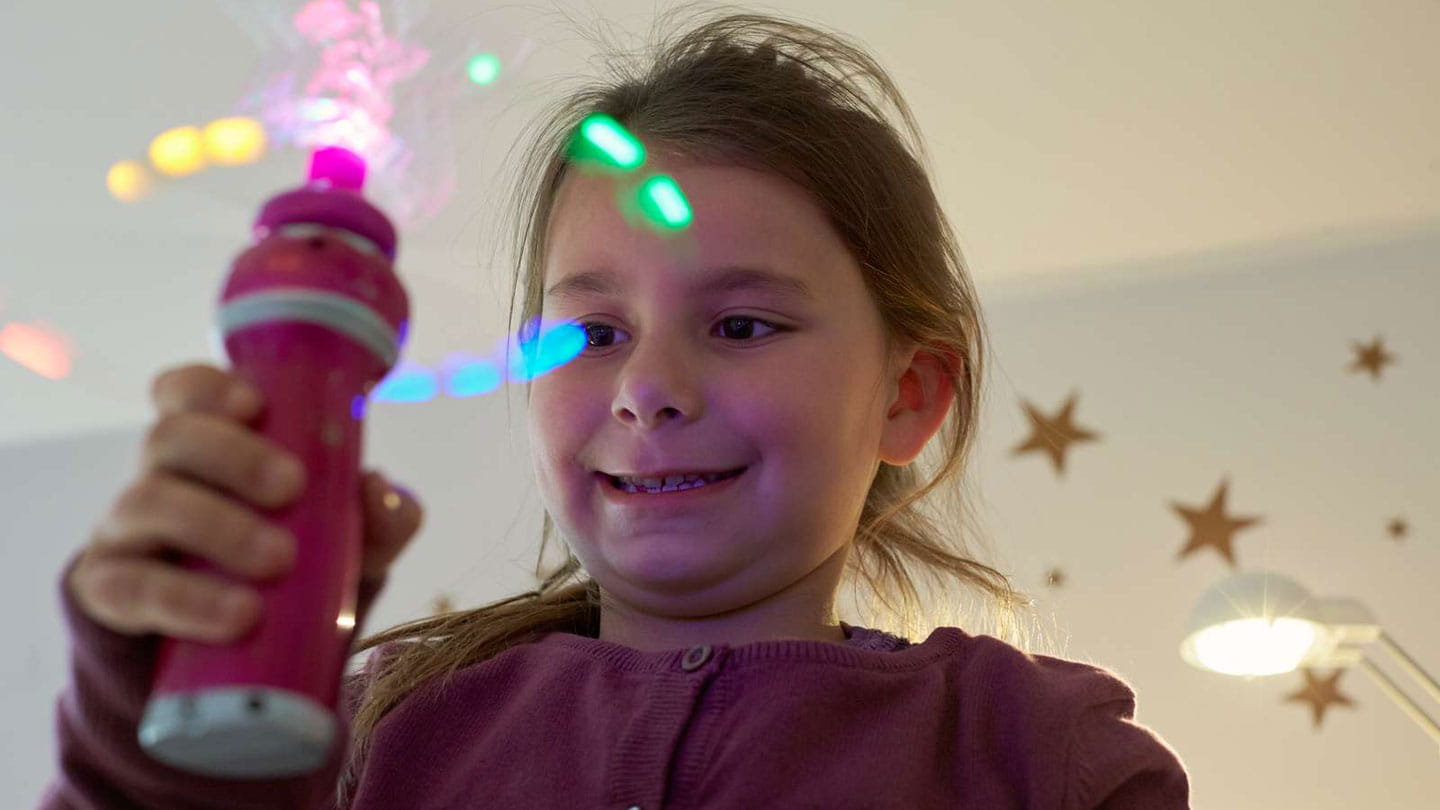 Young girl playing with a toy that is shining multicoloured lights.