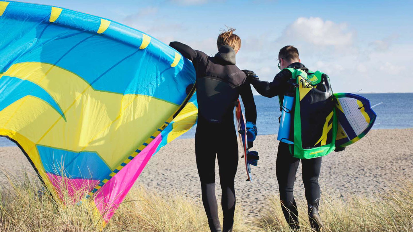 Kite surfers walking together on Amager beach
