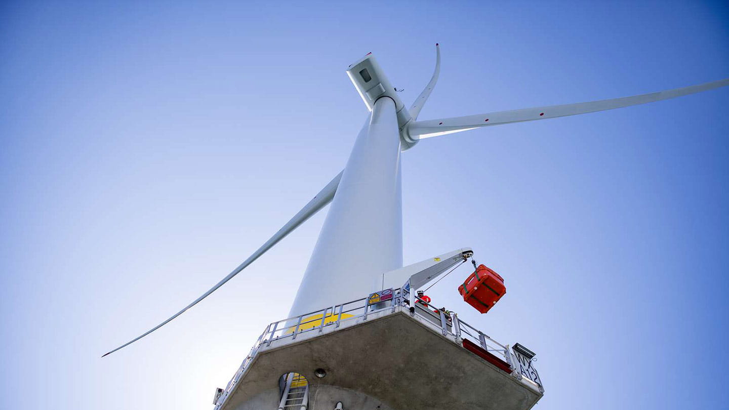 A wind turbine seen from a low-angle shot with a clear blue sky.