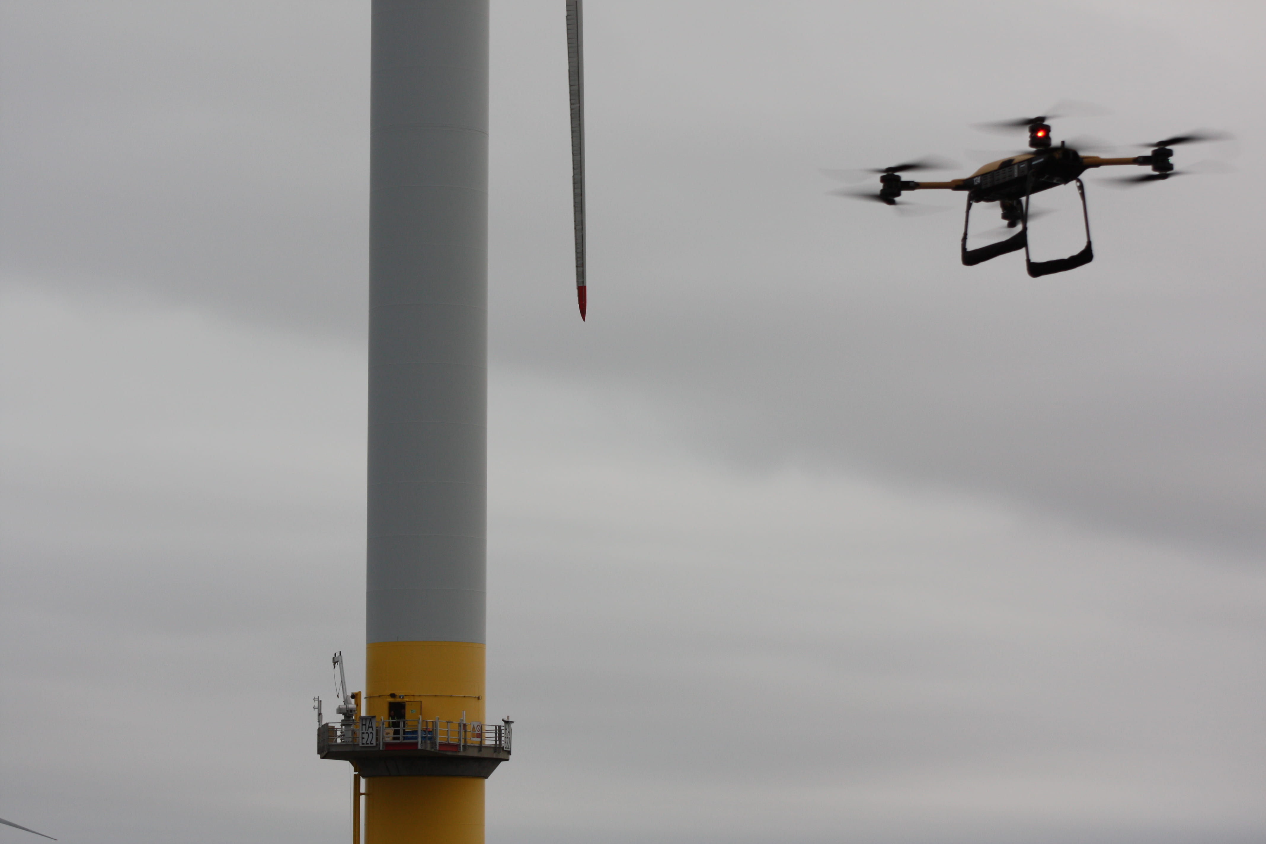 Drone in flight with offshore wind turbine in background