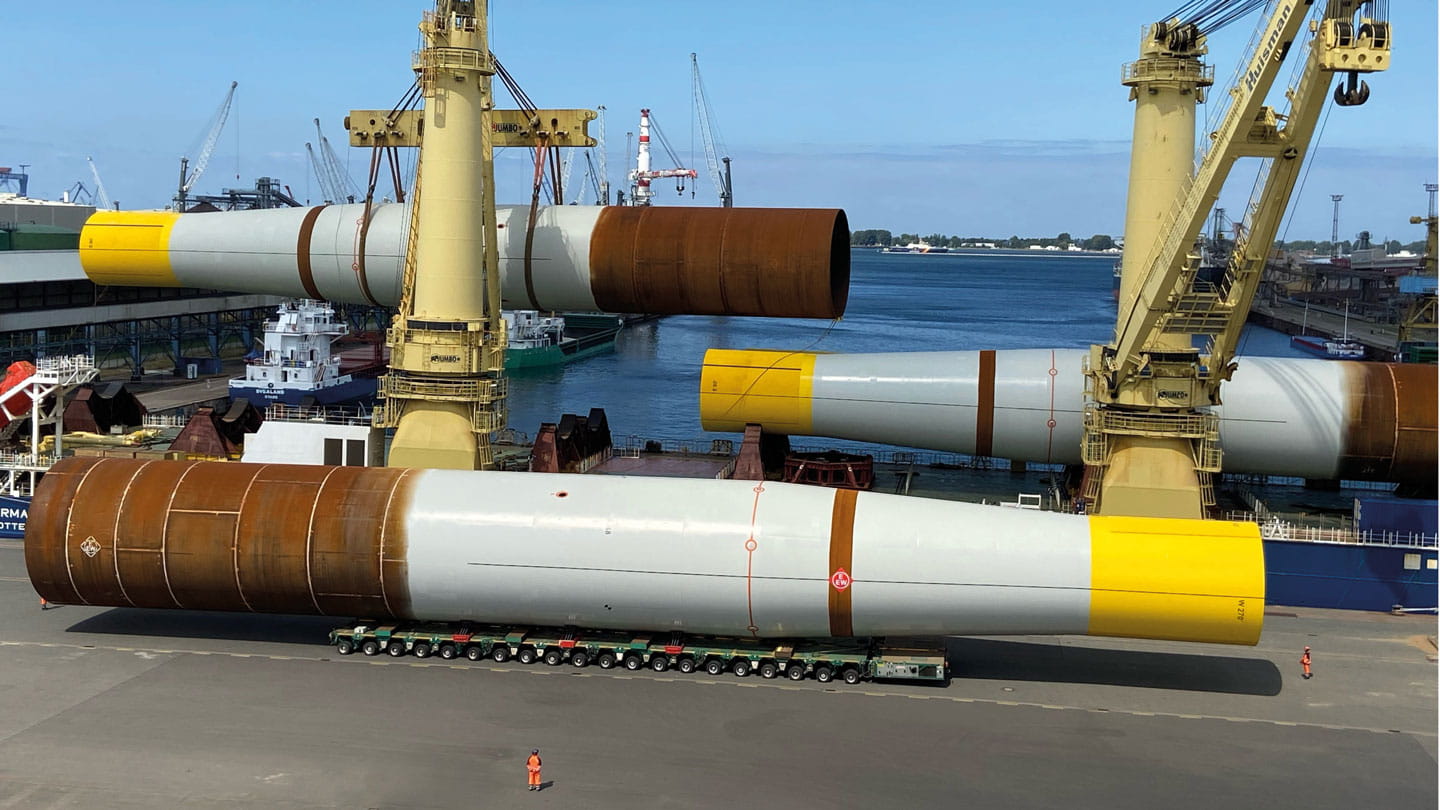 Image showing monopiles being offloaded from the delivery vessel for storage, before being transferred to the installation vessel.