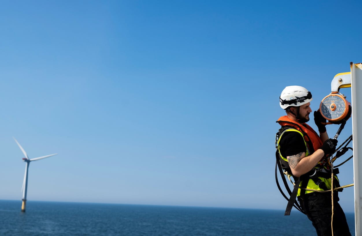 Images shows person inspecting an offshore wind turbine