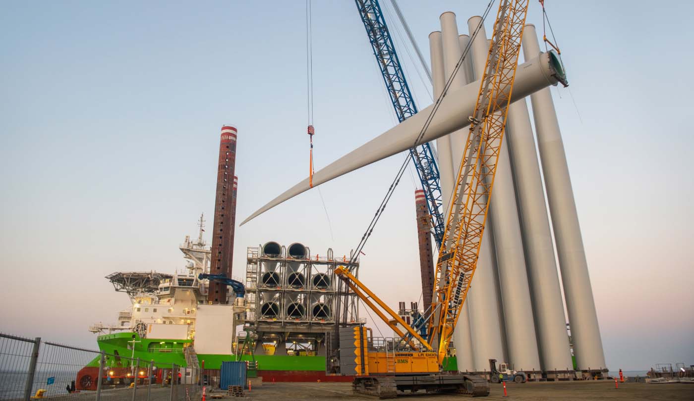 A blade for an offshore wind turbine being lifted by a crane, part of Ørsted's growing offshore wind supply chain.