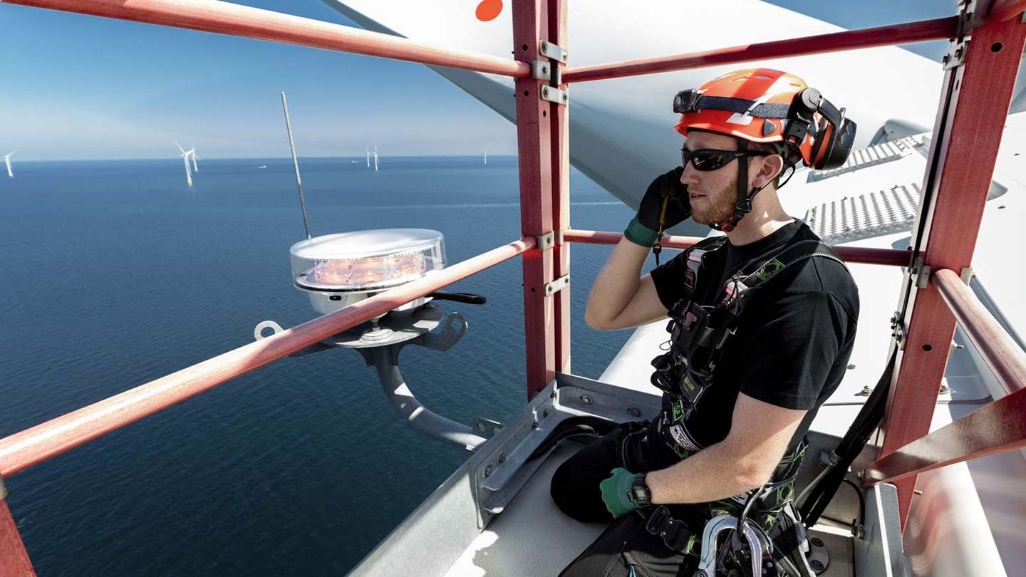 An Ørsted technician on top of an offshore wind turbine, showing how to build an offshore wind farm like Sunrise Wind.